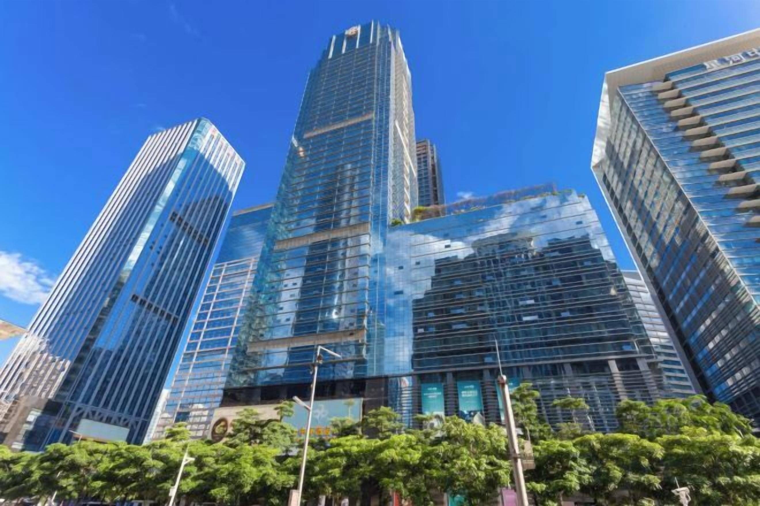 Un immeuble de grande hauteur doté d’une façade moderne en verre, entouré d’autres bâtiments imposants.