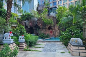 Jardí paisatjistic amb una formació rocosa, una petita piscina i estàtues d'animals.