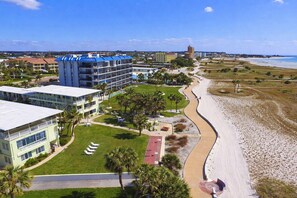Un hotel frente al mar con varias construcciones, una playa y cielo despejado.
