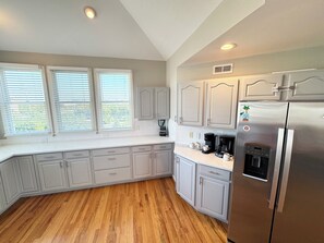 Una cocina con gabinetes blancos, un refrigerador de acero inoxidable y una cafetera.