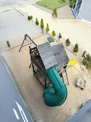 Un parque infantil con un tobogán, columpios y una mesa pequeña.