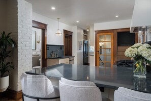 Una cocina moderna con una isla grande, taburetes de bar, un refrigerador y un comedor con vistas.