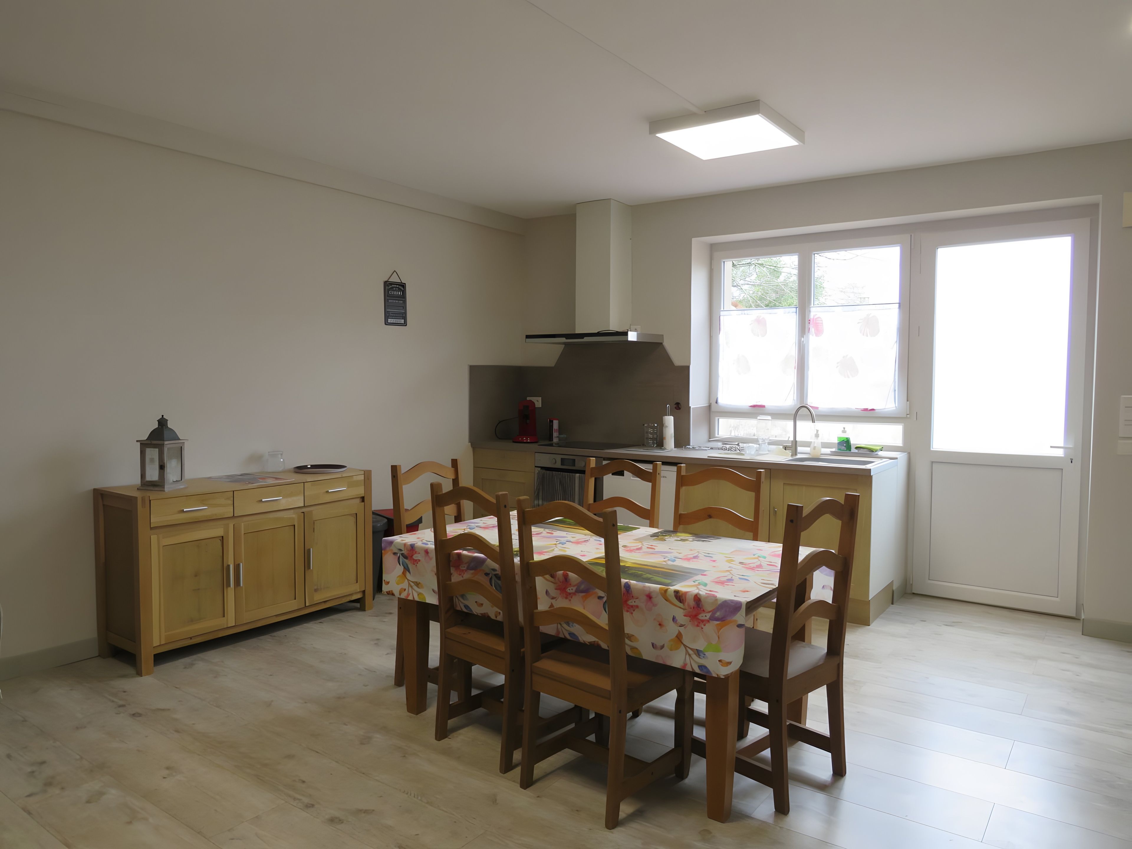 A dining area with a table and chairs, a kitchen with a stove and sink, and a window with a view.