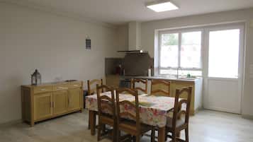 A dining area with a table and chairs, a kitchen with a stove and sink, and a window with a view.