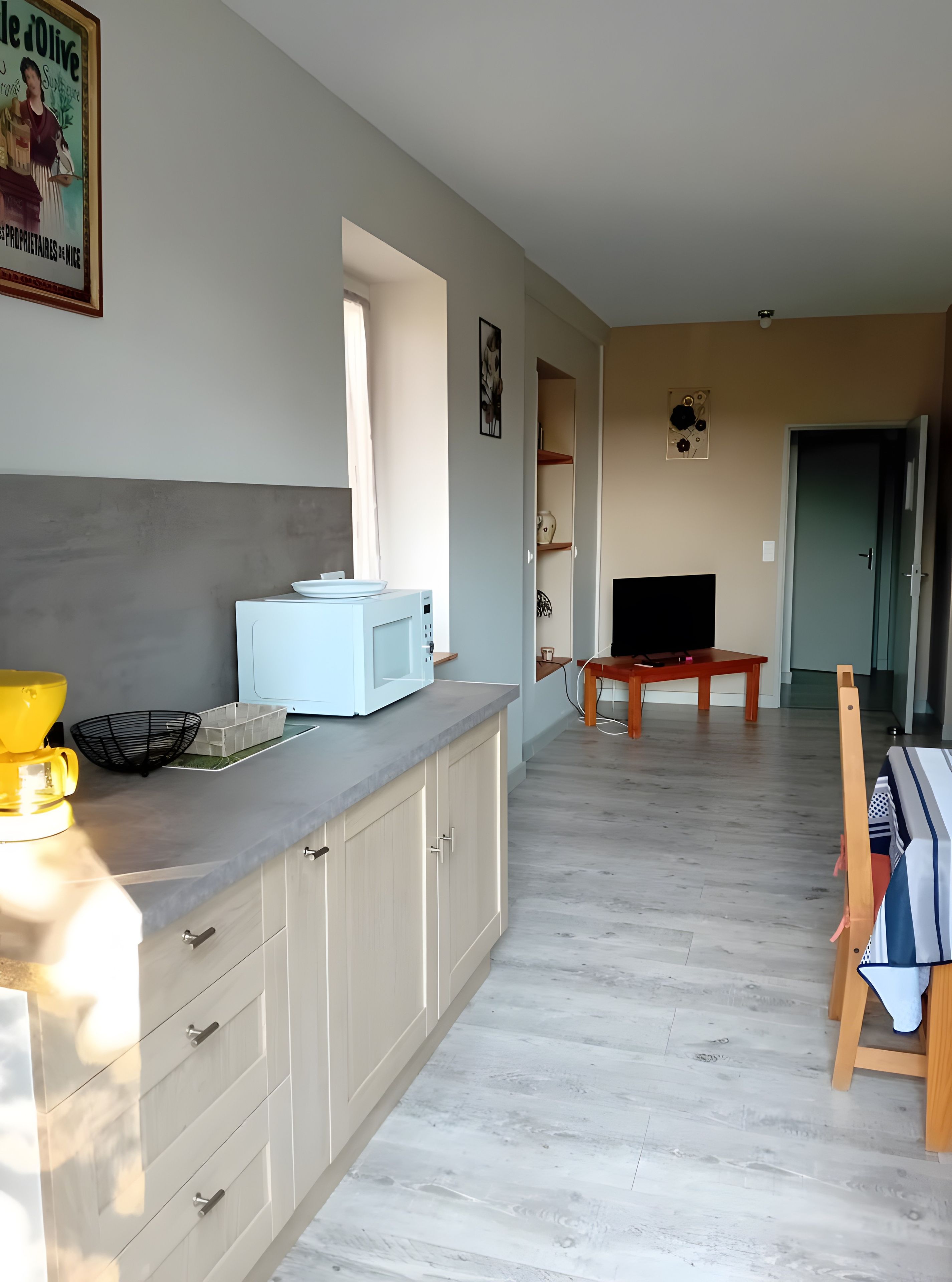 Eine moderne Küche mit Mikrowelle, Kaffeemaschine und Spüle. Es gibt einen Essbereich mit Tisch und Stühlen sowie einen Fernseher auf einem Schrank.
