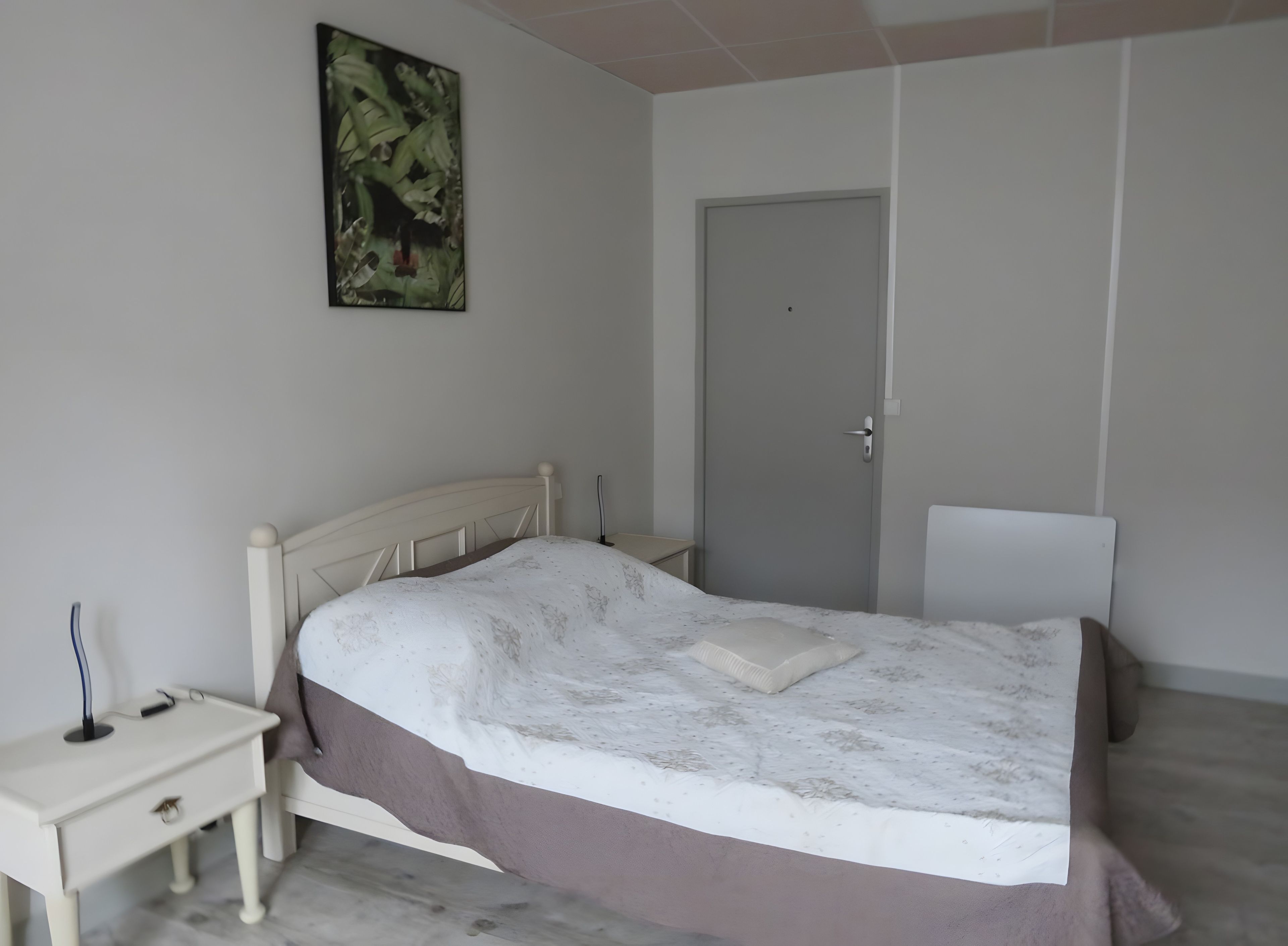 Ein Schlafzimmer mit einem Bett, einem Nachttisch und einer Tür.