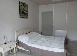 A bedroom with a bed, bedside table, and a door.