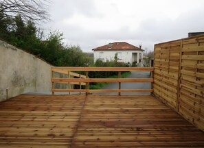 Eine Holzterrasse mit Blick auf ein Haus und Grünflächen.