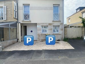 Een gebouw met een bord waarop restaurant en bar staan aangegeven, twee parkeerplaatsen gemarkeerd met 'P', en een bord met het nummer '2' op het gebouw.
