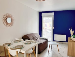 Een eetgedeelte met een witte tafel gedekt voor vier personen, een bruine bank en een kleine witte tafel.