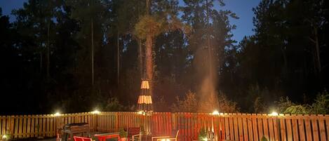 An outdoor patio area with a fire pit, seating, and a wooden fence.