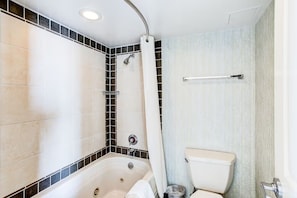 Et badeværelse med badekar, toilet og bruseområde.