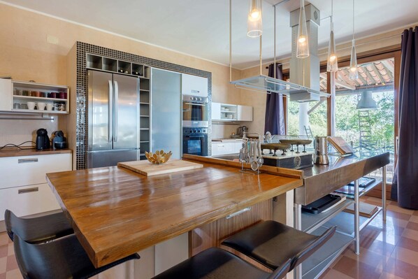 Una cocina moderna con una isla central, electrodomésticos de acero inoxidable y vistas al exterior.