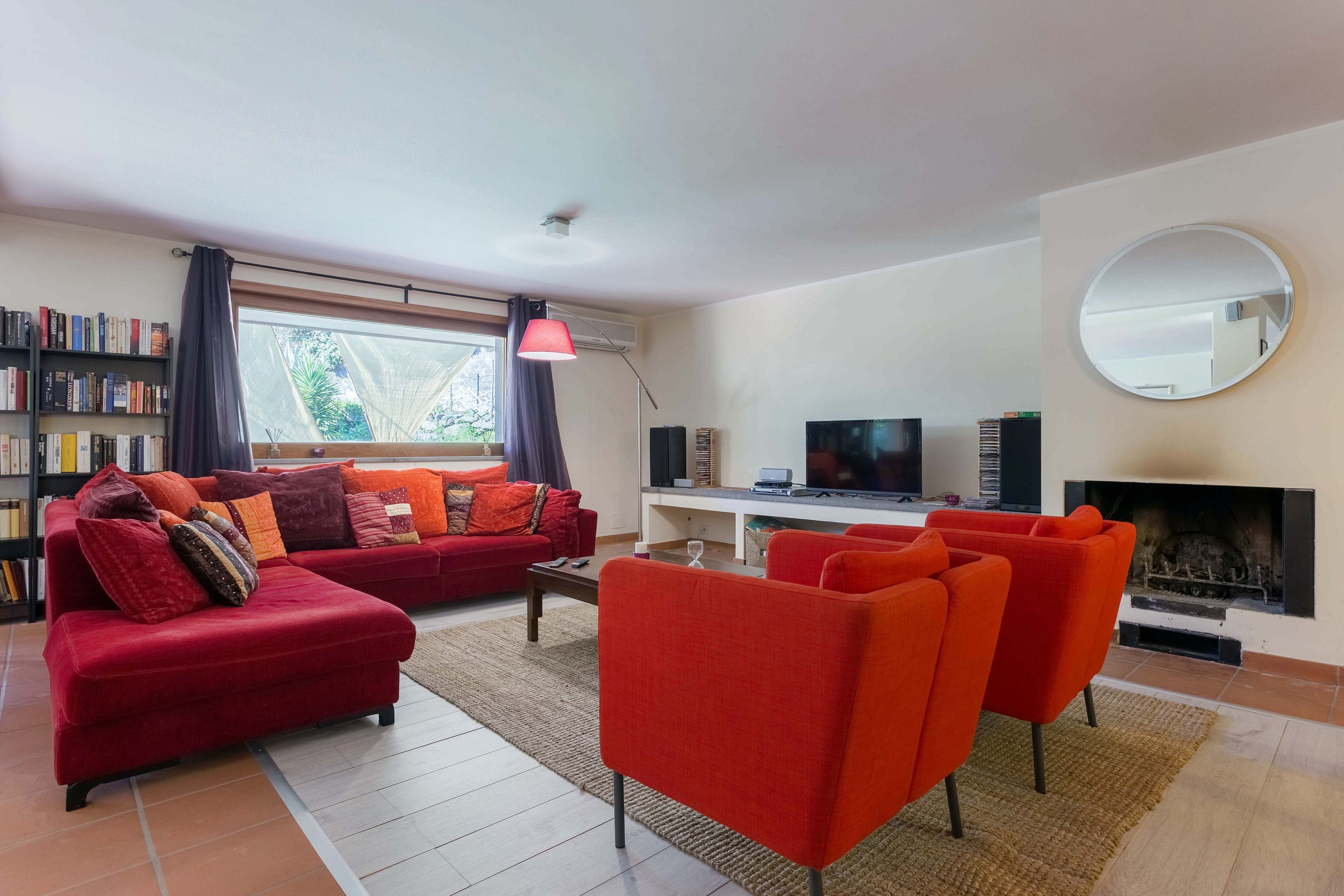 A living room with a red sofa, a TV, a fireplace, and a bookshelf.