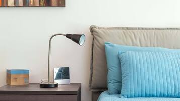A neatly arranged bedroom with a bed, a nightstand, a lamp, and a wall-mounted picture frame.