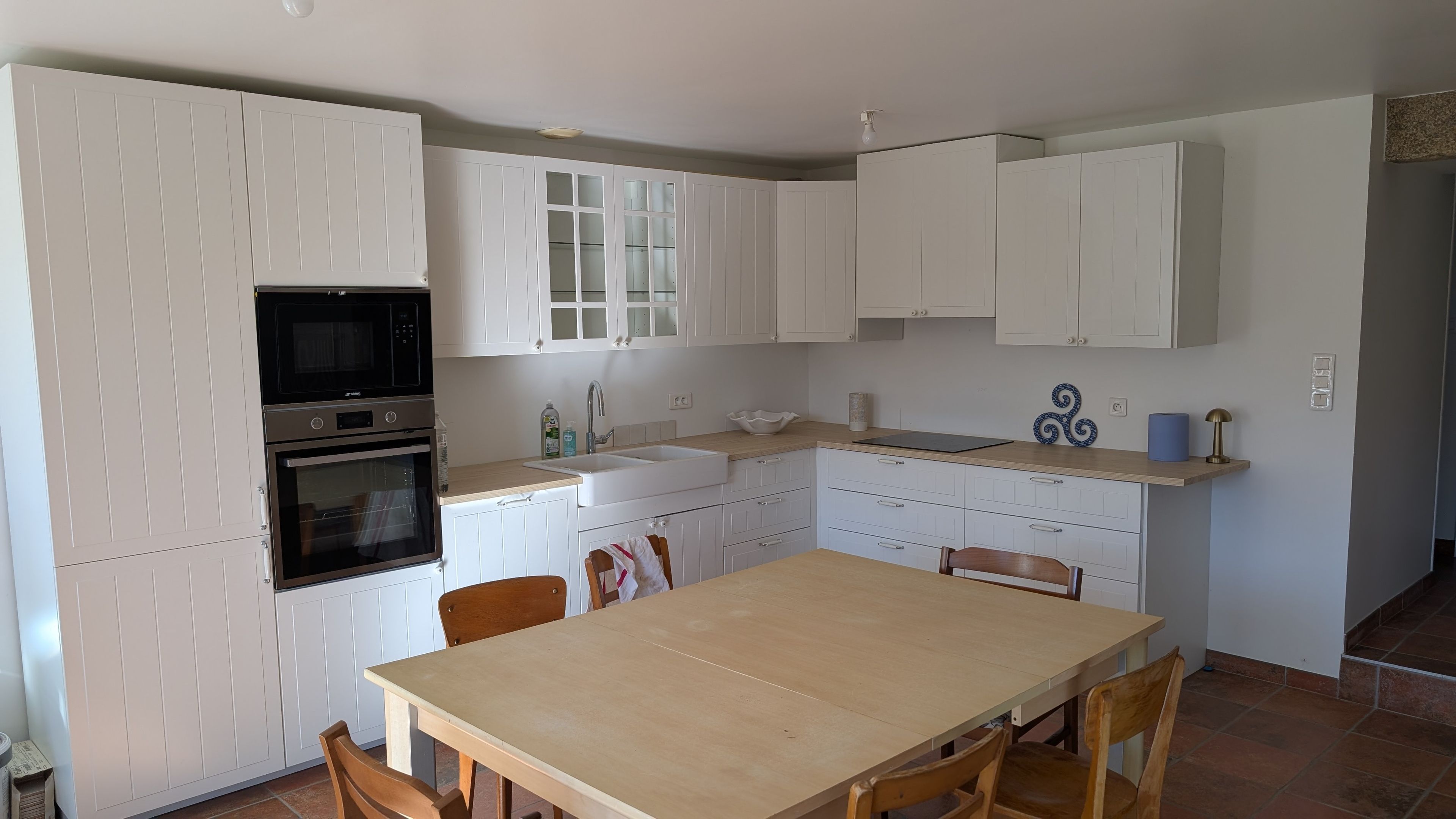 A modern kitchen with white cabinetry, a built-in oven, a microwave, and a sink.