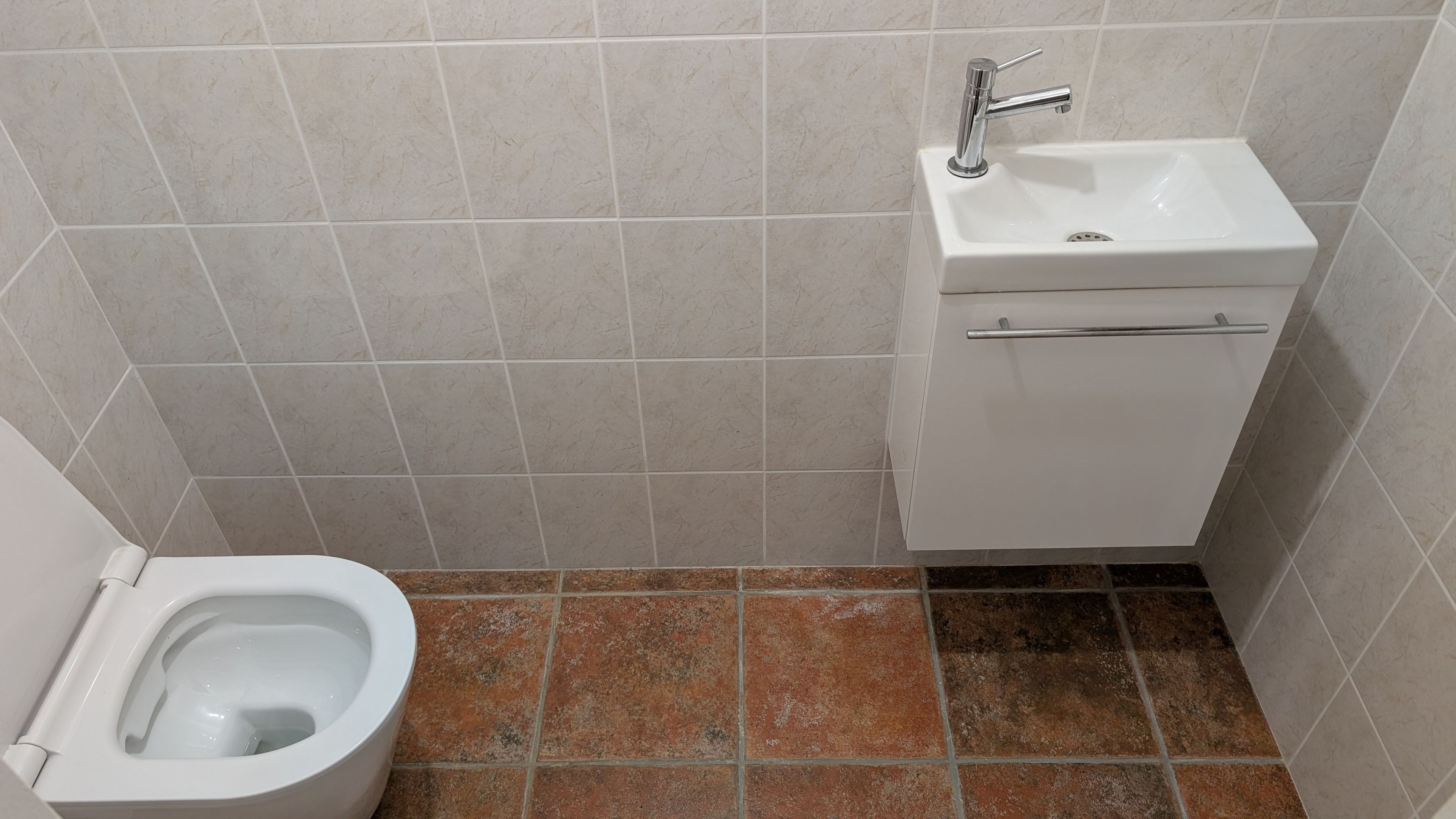 A bathroom with a toilet, sink, and tiled walls.