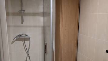 Un baño con ducha de vidrio, un armario de madera y una bañera blanca.