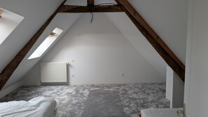 A room with a sloped ceiling, a radiator, and a bed. - Manoir de Kermarec – A Peaceful Stay between Countryside and Forest in Pontivy (Pontivy)