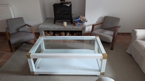 Una sala de estar con una mesa de centro de vidrio, dos sillones, una chimenea y un radiador.