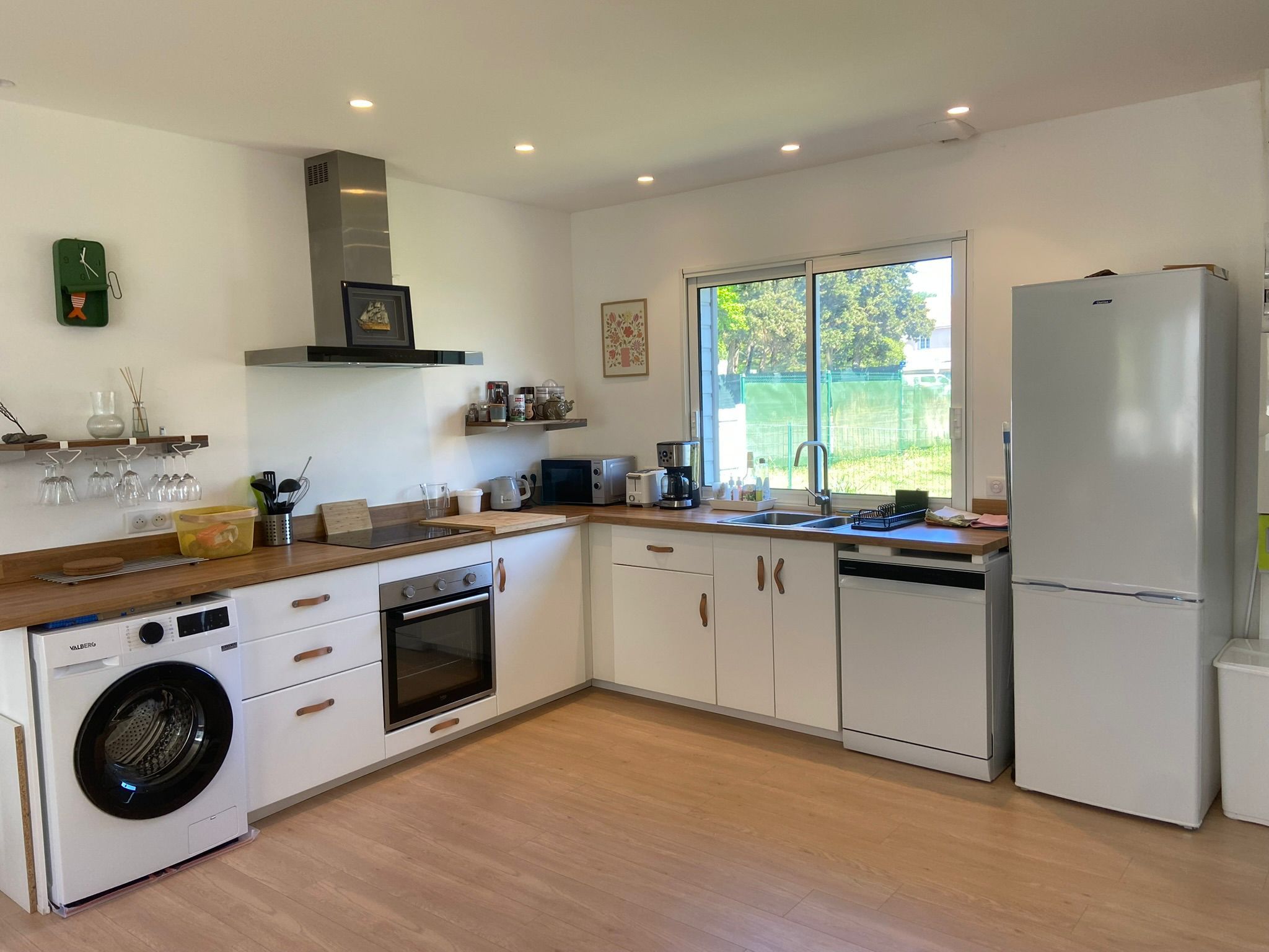 A modern kitchen with a built-in oven, dishwasher, and a large refrigerator.