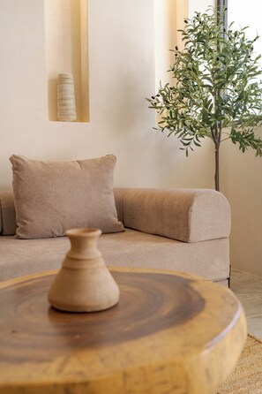 A modern living room with a beige sofa, a wooden coffee table, and a potted plant. - OTONONOMUS TOWER (Tulum)