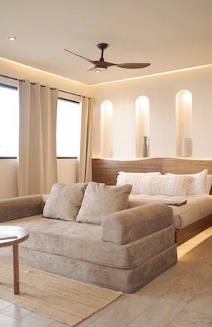 A modern bedroom with a bed, a sofa, and a ceiling fan. - OTONONOMUS TOWER (Tulum)