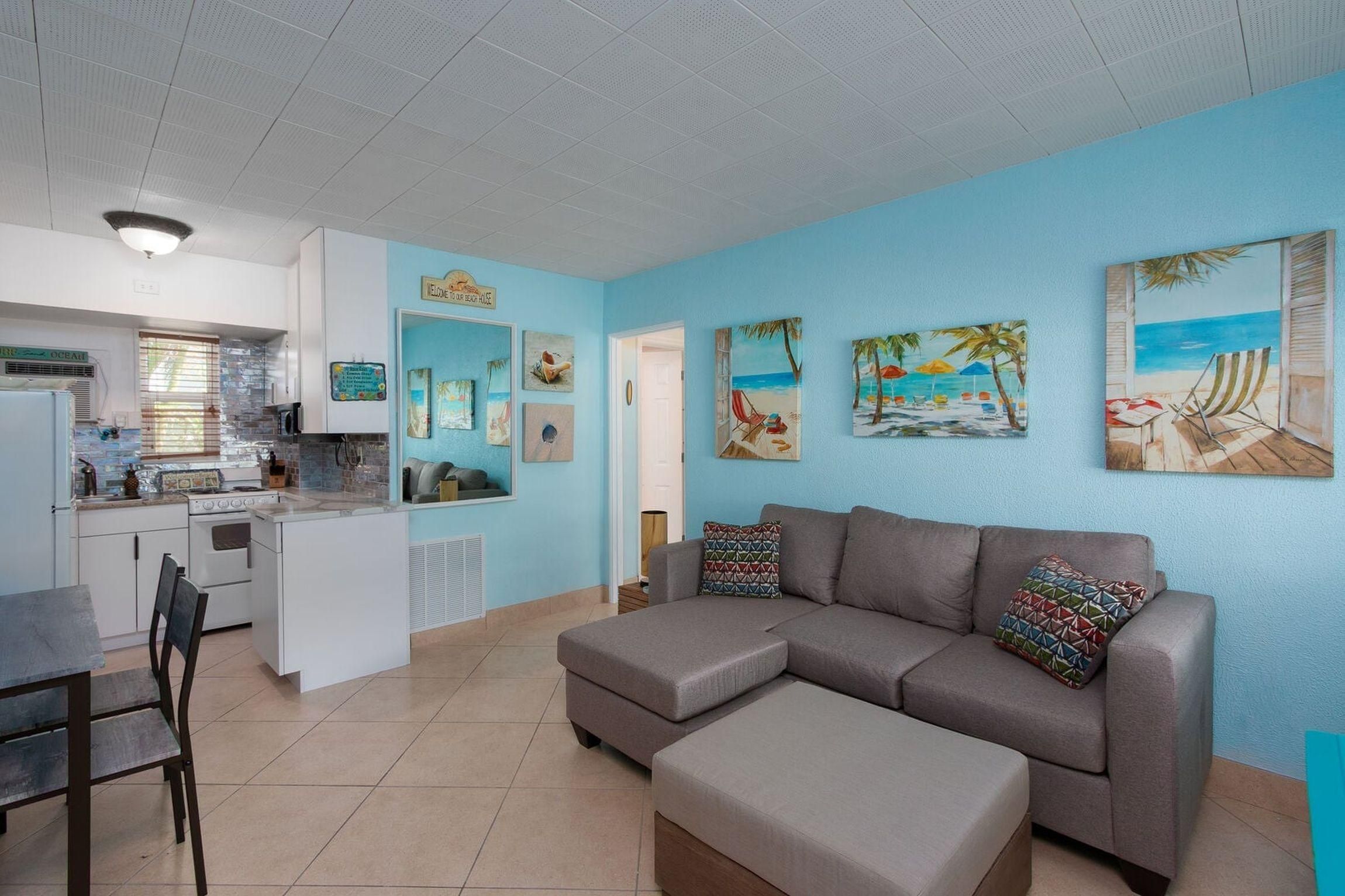 Una sala de estar con sofá, una mesa de comedor y una zona de cocina con refrigerador y estufa.