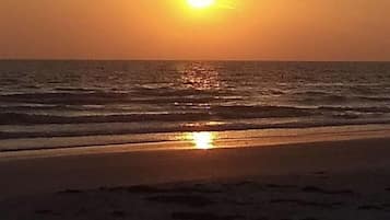 A sunset over the ocean with waves on the shore.