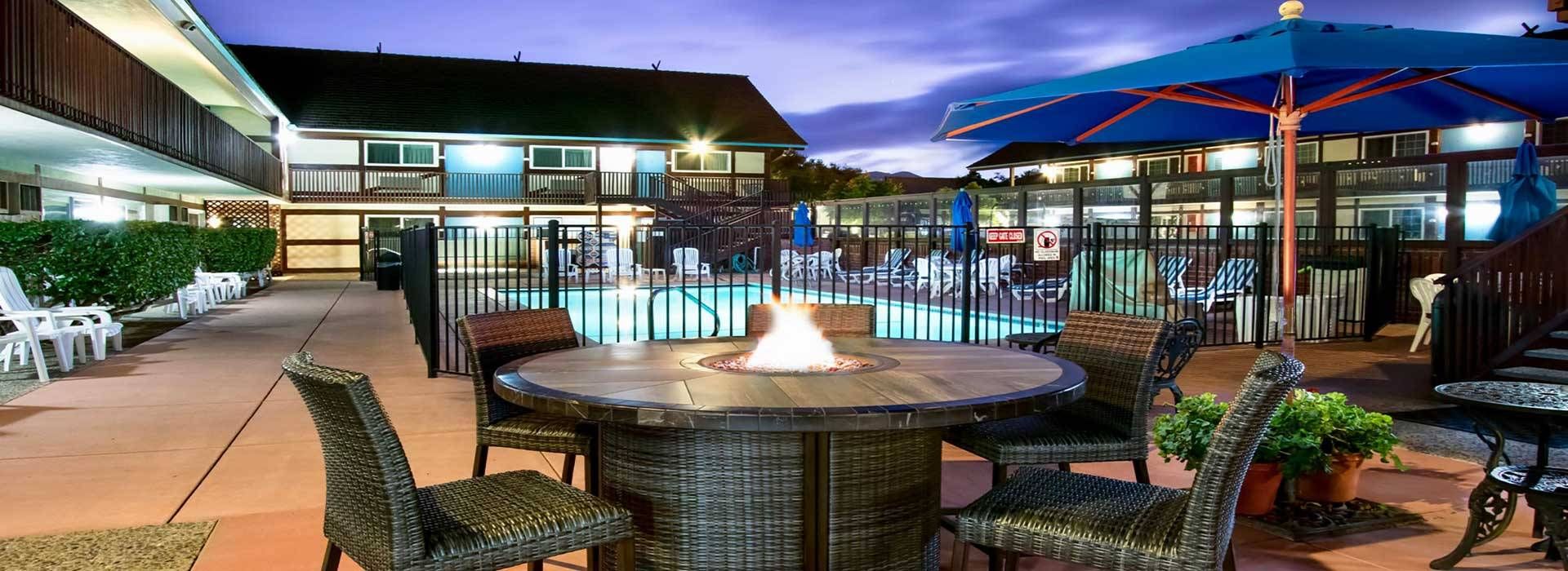 An outdoor pool area with lounge chairs and a fire pit.