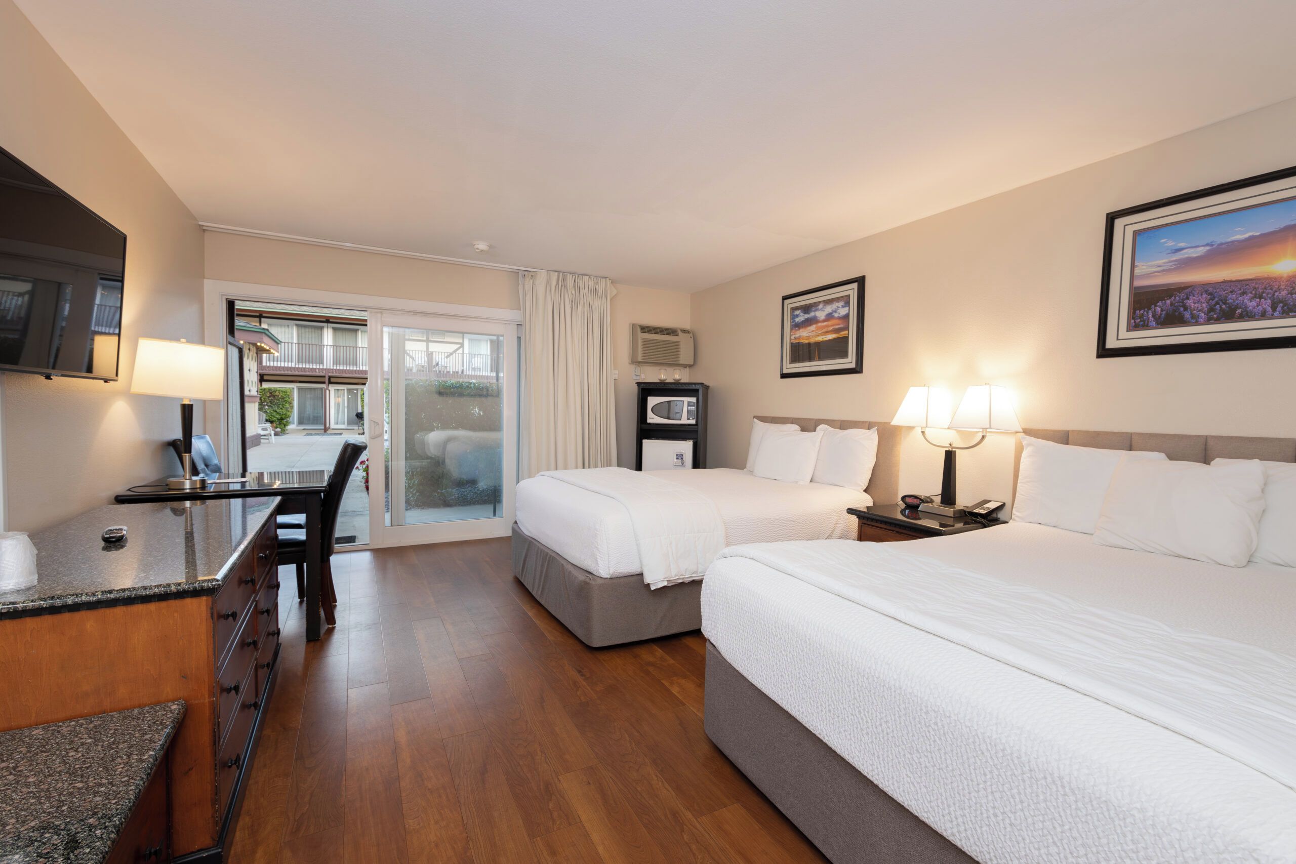 A hotel room with a bed, a desk, a chair, a television, and a window.