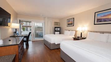A hotel room with a bed, a desk, a chair, a television, and a window.