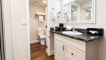 A bathroom with a white toilet, a sink with a granite countertop, and a mirror above the sink.