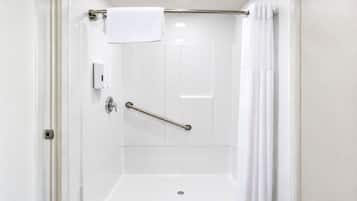 A white bathroom with a shower, a grab bar, and a towel rack.