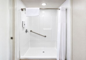 A white bathroom with a shower, a grab bar, and a towel rack. - Deluxe King with Patio & Direct Pool Access – Downtown Solvang (Solvang)