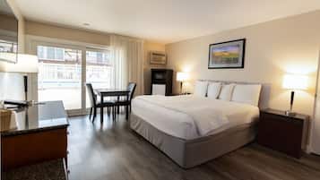 A hotel room with a bed, desk, chair, and a view of the outside.