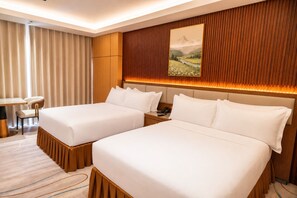 Ein Hotelzimmer mit zwei Betten, einem Schreibtisch und einem Stuhl.