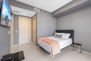 A bedroom with a bed, bedside tables, a TV mounted on the wall, and a door leading to another room. - Terrific 3-bedroom apartment with AC in vibrant Miami (Miami)