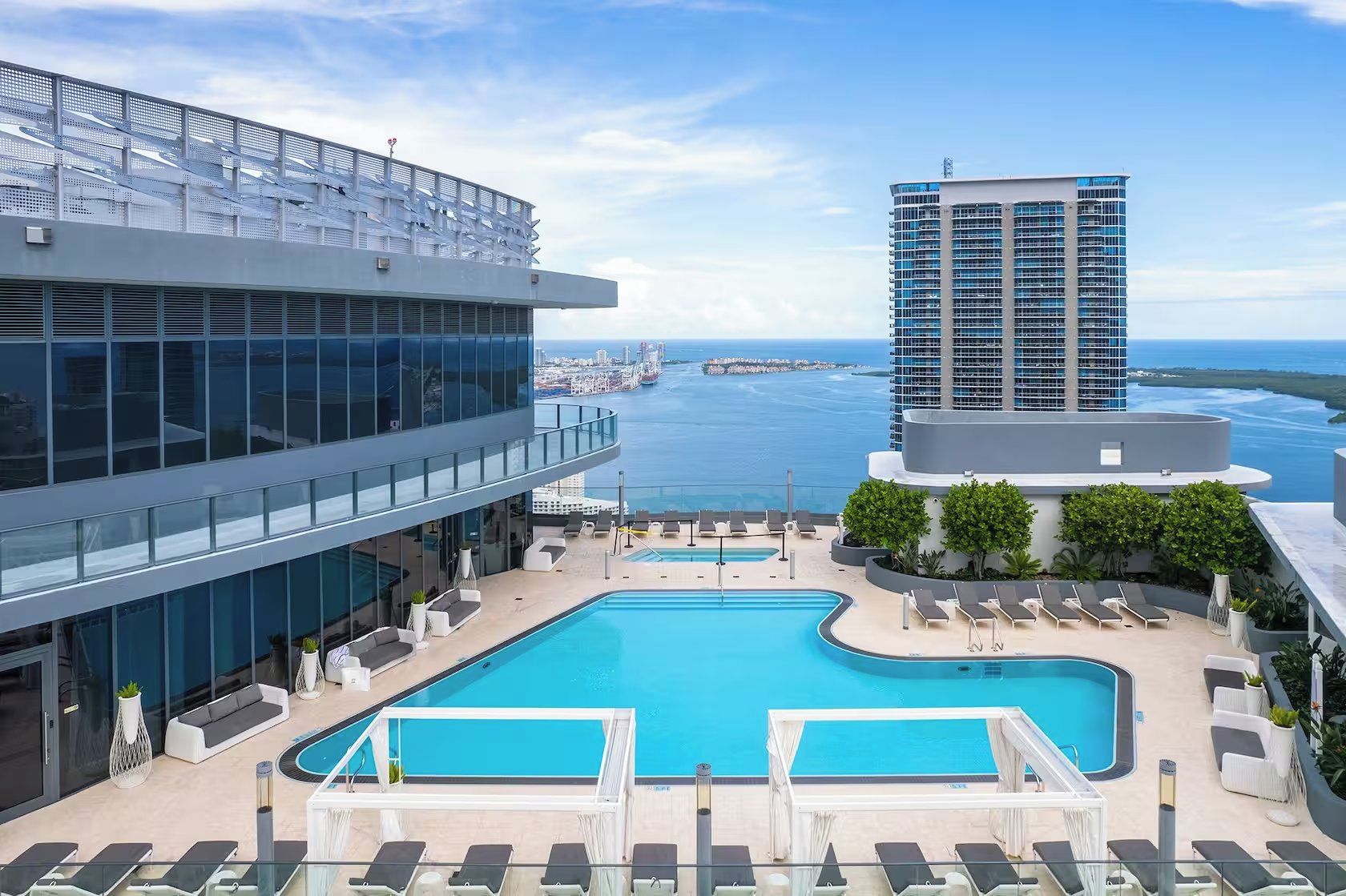 A rooftop pool area with lounge chairs and a view of the ocean.