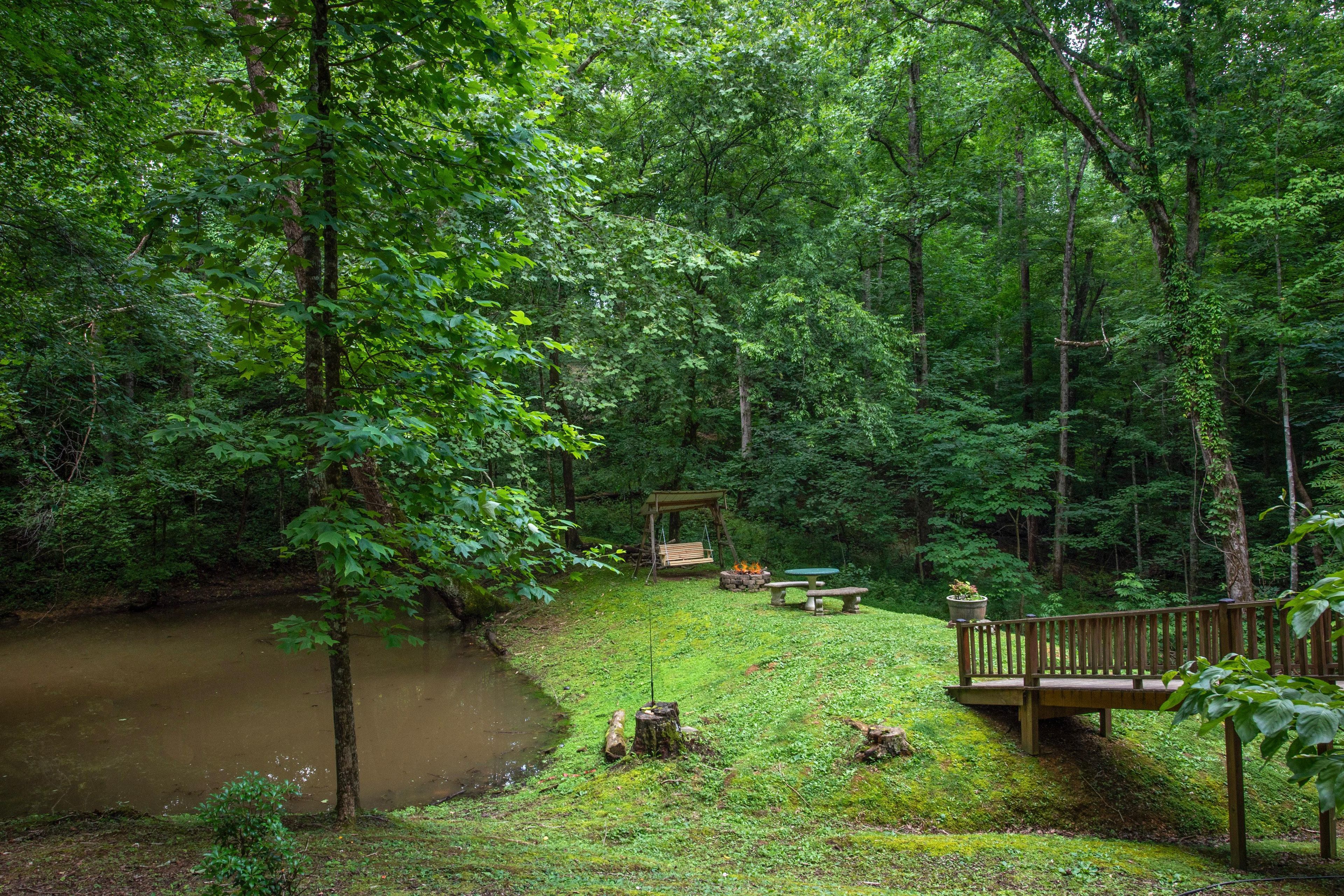A forested area with a wooden deck, a bench, and a small pavilion.