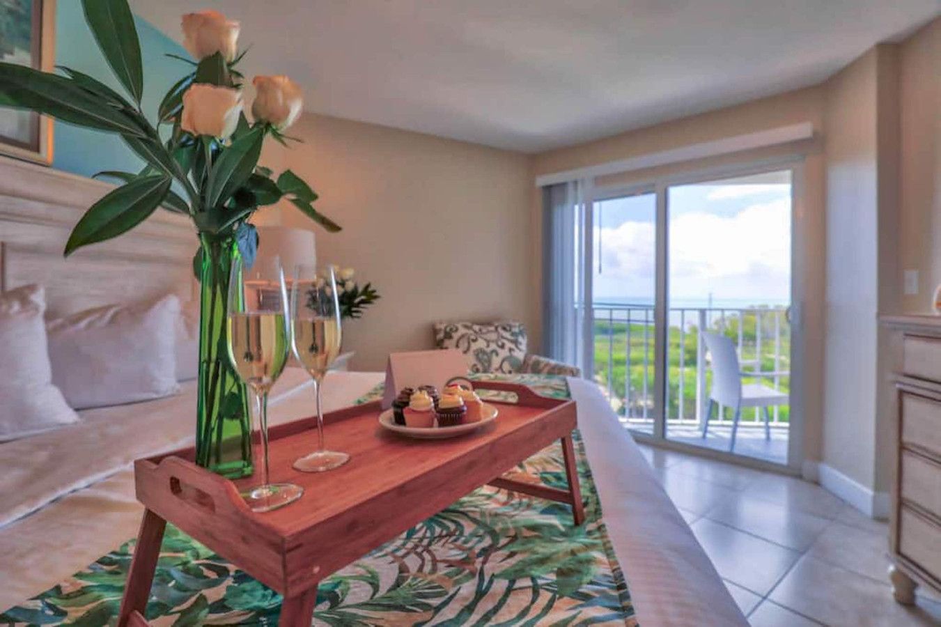 Une pièce avec une table en bois dressée pour un repas, un vase rempli de fleurs et un balcon avec vue.