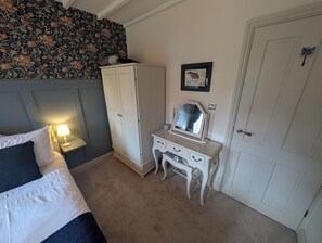 Une chambre à coucher avec un lit, une commode, un miroir et une porte.