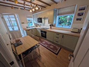 Une cuisine moderne avec un coin repas, un plancher en bois et une vue sur la verdure environnante.