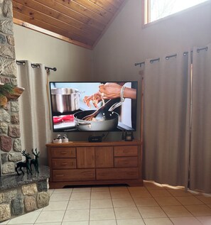 Een televisie bevestigd aan een houten kast, een stenen muur en een raam met gordijnen.