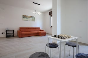 Un salon moderne avec un canapé, une table d’échecs et un tableau accroché au mur.