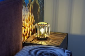 Une lampe au design cylindrique, posée sur une table de chevet en bois.
