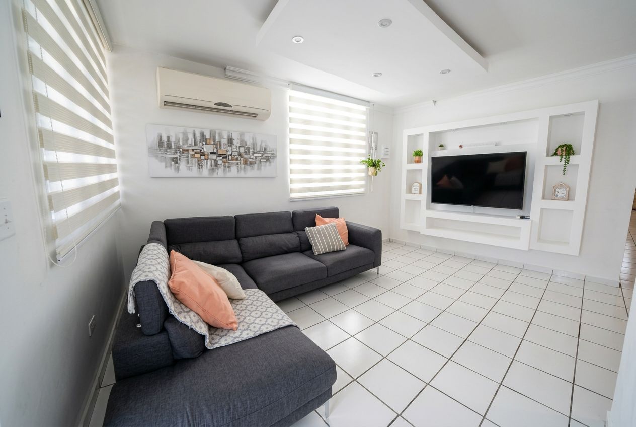 A modern living room with a sectional sofa, a flat-screen TV, and a cityscape artwork.