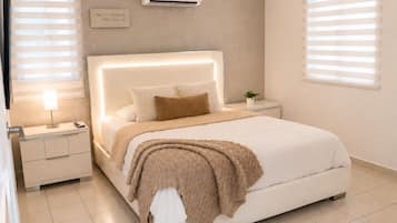 Une chambre à coucher moderne avec un grand lit, des tables de chevet, un climatiseur et une citation inspirante sur le mur.