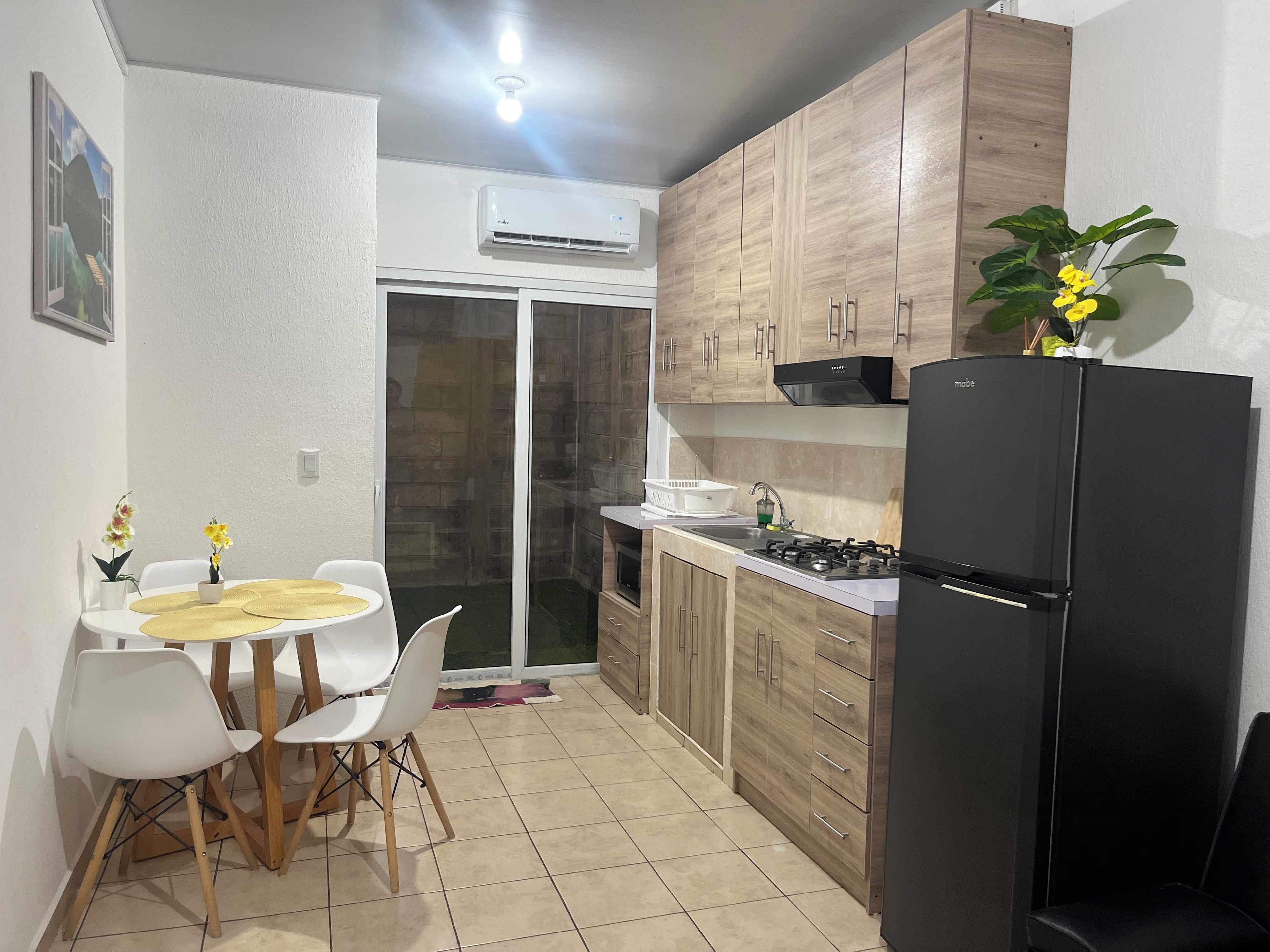 A compact kitchen with a refrigerator, stove, and white cabinets.
