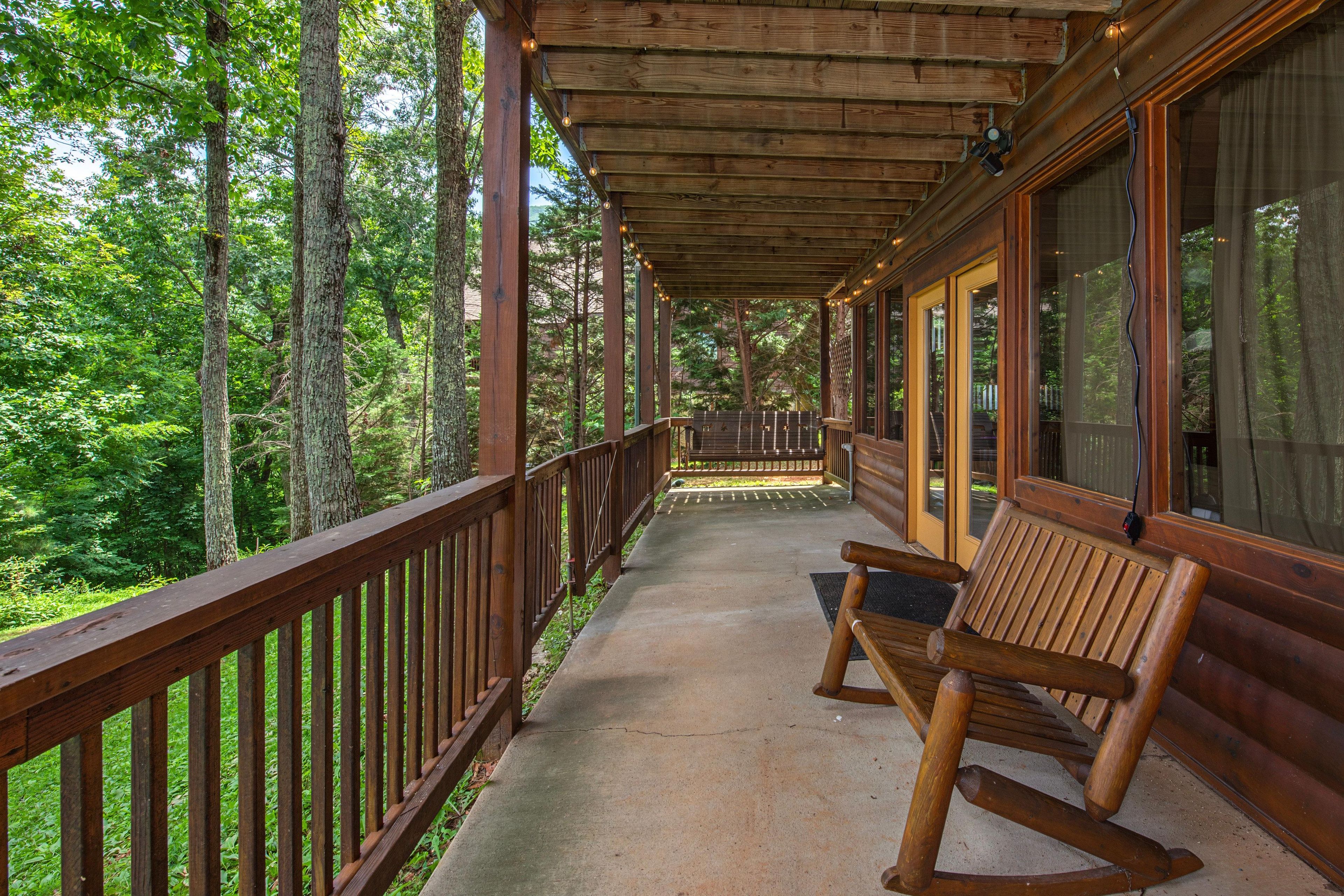 Une terrasse en bois avec un banc, entourée d’arbres.